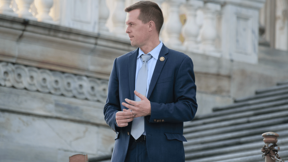 Congressman Jared Golden of Maine standing on the steps of the U.S. Capitol, wearing a blue suit. 