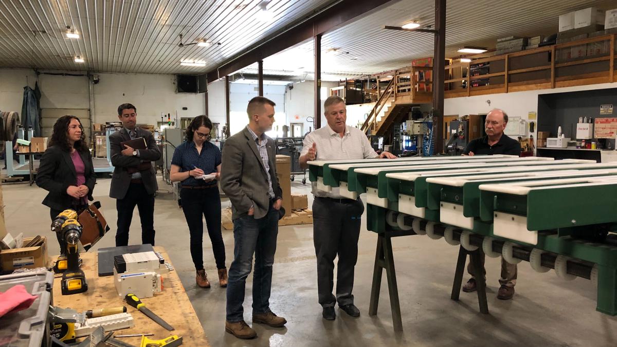 Congressman Jared Golden examining equipment with crowd.