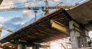 Stock photograph of a bridge under construction, with cranes operating over the bridge platform.