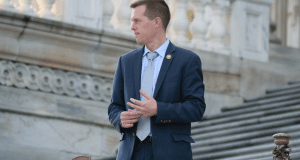 Congressman Jared Golden of Maine standing on the steps of the U.S. Capitol, wearing a blue suit. 