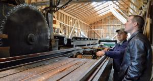Congressman Jared Golden looks at building with saw.