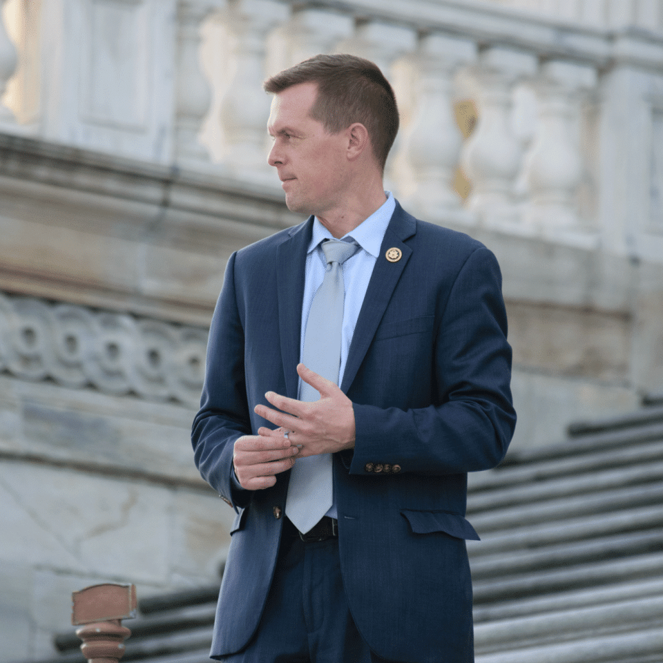 Congressman Jared Golden of Maine standing on the steps of the U.S. Capitol, wearing a blue suit. 