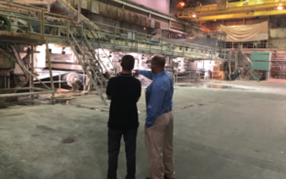 Congressman Jared Golden pointing at industrial site with another man.